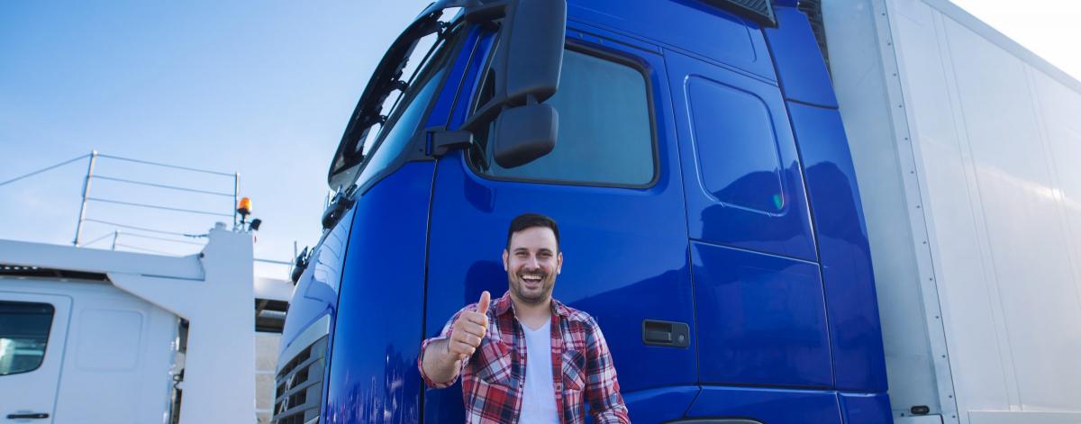 Un routier souriant devant son véhicule poids lourd